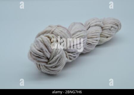 Isolated ball or skein or ball of hand spun hand-dyed oatmeal colored wool or yarn on a white background Stock Photo