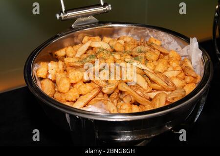 French fries and hash brown inside a buffet pan. Depp fried snacks on a buffet tray. Stock Photo