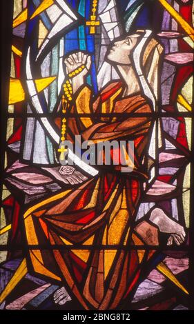 LOS ANGELES, UNITED STATES - Mar 13, 1990: Stained Glass image of St. Bernadette praying to Blessed Mother in Lourdes grotto. Stock Photo