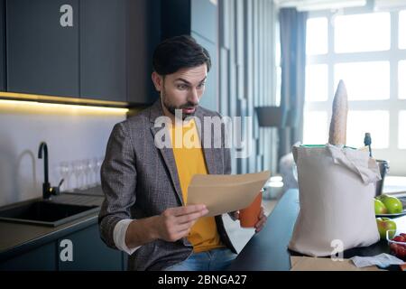 Young man looking shocked lookig at the bill from the store Stock Photo