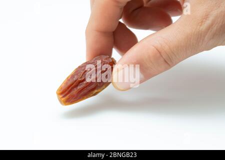Hand holding  pitted dates isolated on white background Stock Photo