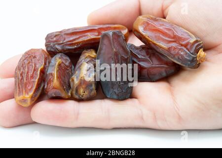 Hand holding  pitted dates isolated on white background Stock Photo