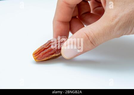 Hand holding  pitted dates isolated on white background Stock Photo