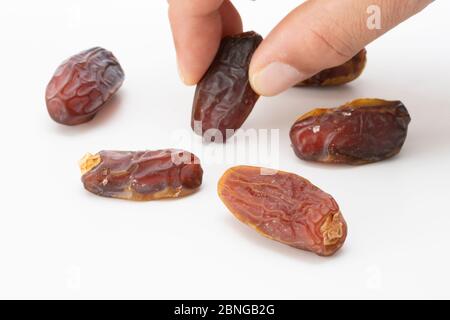 Hand holding  pitted dates isolated on white background Stock Photo