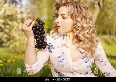 Happy woman with grape at a picnic in summer garden Stock Photo