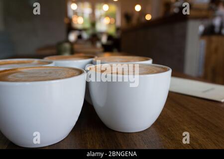 Cups with cappuccinos on a wooden table in the cafe Stock Photo