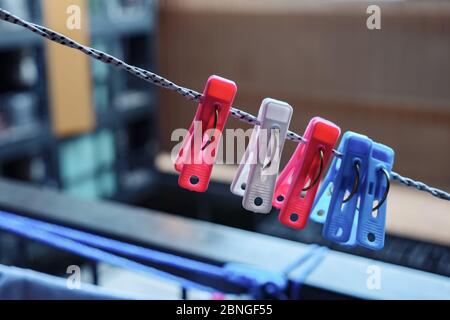 small colorful clothespins on white and black rope on balcony against blurry building closeup Stock Photo