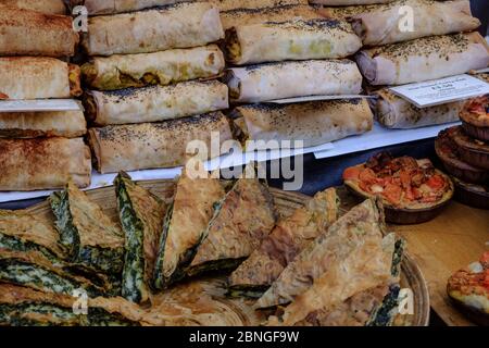 Display of spinach and cheese burek and Thai curry rolls for sale at open air market. Portobello Road, Notting Hill, West London, England, UK. Stock Photo