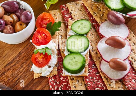 Beetroot and rye flour crackers with vegetables for making snacks on a wooden background. Vegetarianism and healthy eating Stock Photo