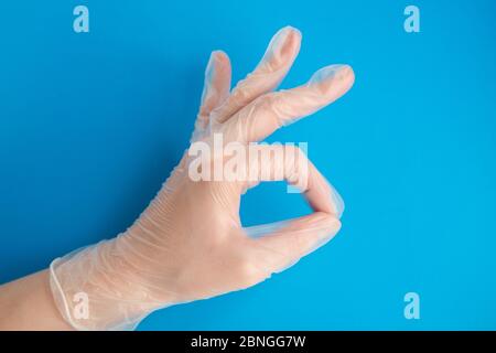 Doctor hand in Medical Latex Glove making OK Sign on blue background Stock Photo