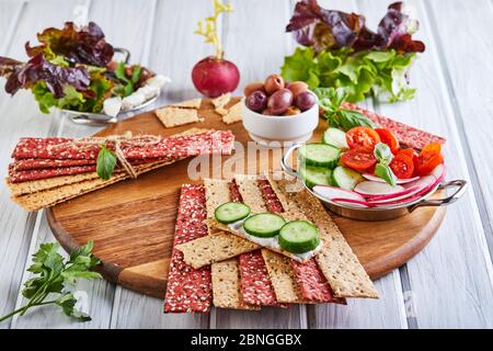 Beetroot and rye flour crackers with vegetables for making snacks on a wooden background. Vegetarianism and healthy eating Stock Photo