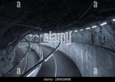 Sci fi looking dark and moody underground parking lot with fluorescent lights on.  Crossing roads, exit way Stock Photo