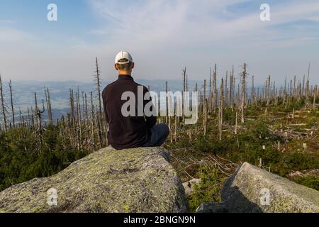 Young man tourist sittiing on top of mountain, Sumava National Park and Bavarian Forest, Czech republic and Germany Stock Photo