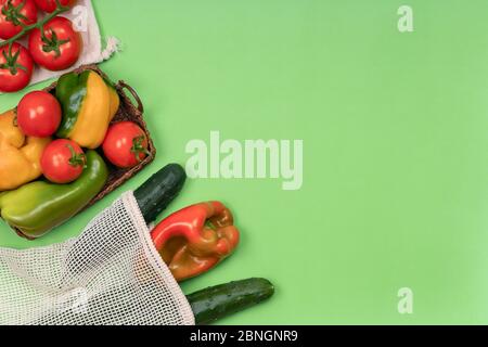 Grocery in reusable eco friendly cotton mesh bag and wicker basket on green. Sustainable lifestyle. Vegetables from local farmers market in textile ba Stock Photo