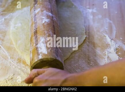 Woman hands kneading, rolling yeast dough on table with flour. Preparing for yeast cake Stock Photo