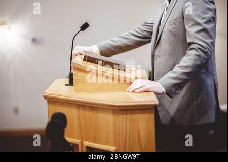 Selective focus shot of a male standing and speaking from the pulpit Stock Photo