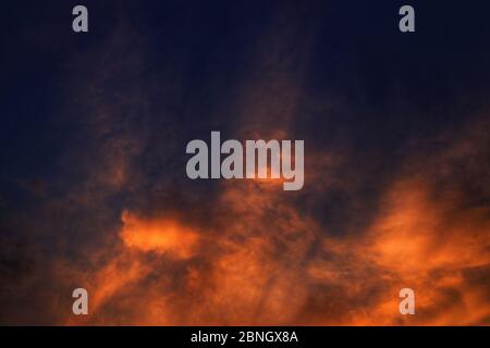 Burning sky, dramatic red colour clouds and sun ray shining through the heaven. God light and enigmatic powerful emotion. colour of nature. moody and Stock Photo
