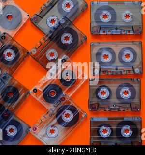 Creative colorful background with audio cassettes. Group of plastic cassettes with music records of the 80s on an orange background. A variety of musi Stock Photo
