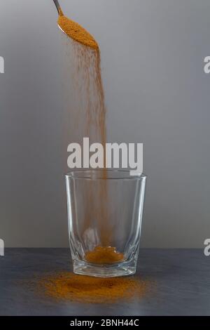 Coffee falling from spoon to empty glass on stone desk Stock Photo