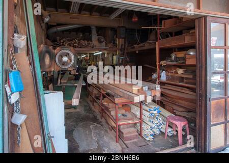 Street wood workshop in Thailand. Circular machine. A lot of long bars and blanks for work. Many shelves. Horizontal. Stock Photo