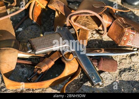 First World War pistol and sewn riveted leather cases placed on the stone of the street. Stock Photo