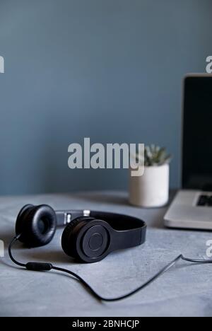 Empty workspace with laptop, headphones and plant at stone grey wall background. Working from home concept. Stock Photo