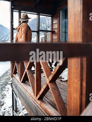 Woman in hat with her dog at wooden house in the mountain resort at winter Stock Photo