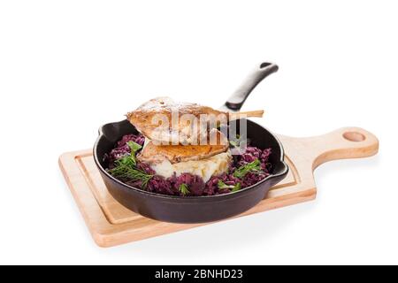 Braised confit duck leg, braised red cabbage, mashed potato in steel fry pan isolated background Stock Photo