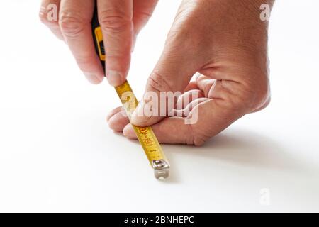 Man working with measuring tape. Close-up of hands holding mesure tape on white background. Stock Photo