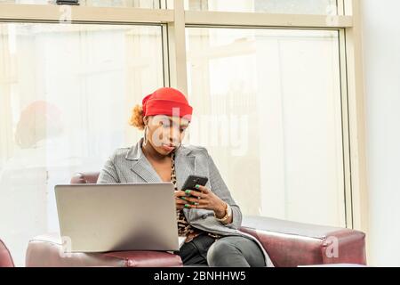 beautiful young african muslim business woman using her laptop computer and smartphone Stock Photo