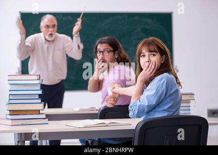 Old teacher and two students in the classroom Stock Photo
