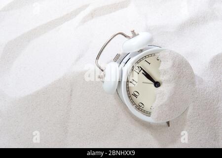 Alarm clock in sand on beach. Vacation time concept Stock Photo