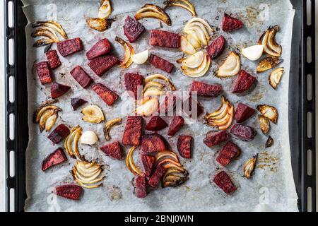 Freshly Baked Beetroot Slices with Onions and Garlic on Oven Tray with Baking Paper Sheet / Beet Chips. Ready to Eat. Stock Photo