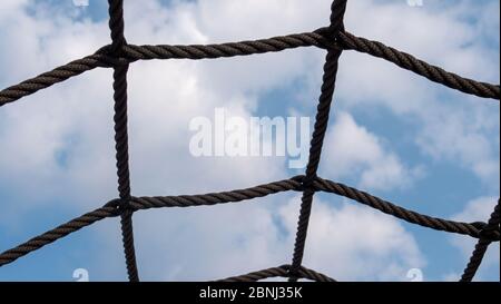 Net of ropes in front of a blue sky with clouds. Stock Photo