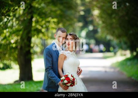 Fabulous young wedding couple posing in the park on the sunny day. Stock Photo