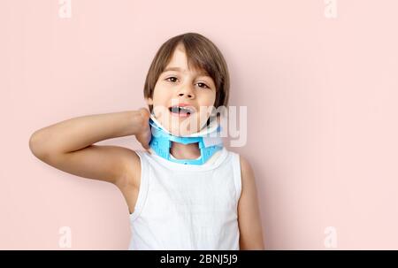 Little boy wearing Head Stabilizer or pediatric Cervical Collar accusing neck pain (Cervicalgia) and Torticollis. Common Childhood Injuries and Preven Stock Photo