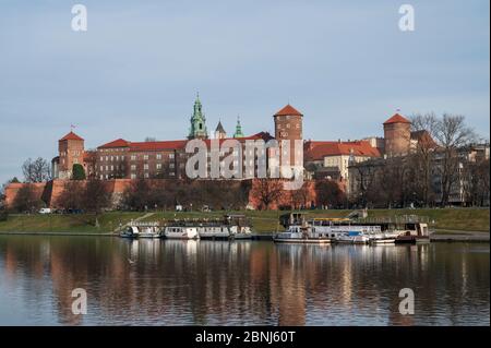 View to Wawel castle, UNESCO World Heritage Site, with restaurant boats moored on Wista (Vistula) River in riverside park, Krakow, Poland, Europe Stock Photo