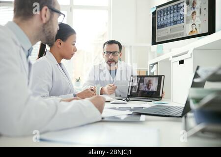 Group of doctors sitting at the table and discussing x-ray images together during a meeting at office Stock Photo