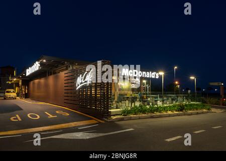 McDonald's fast food restaurant with drive through at night in Imperia, Italy Stock Photo