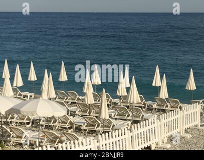white umbrellas and empty sunbeds on the beach, sea view Stock Photo