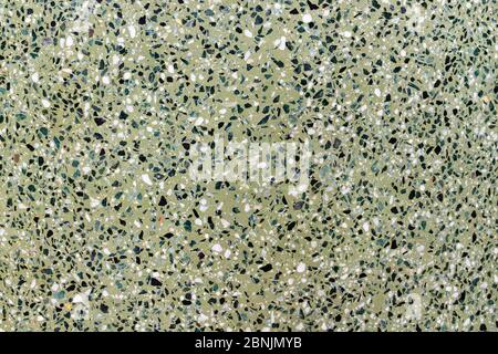 The texture of the mosaic floor is a green shade of marble chips with natural stones, granite, marble, quartz. Polished stone surface. Stock Photo