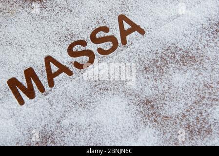 wooden background with sprinkled flour and the word pasta written in Portuguese Stock Photo