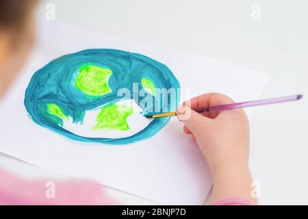 Child draws planet for earth day. Protection of environment. Earth Day celebration. Save world and unity concept. Stock Photo