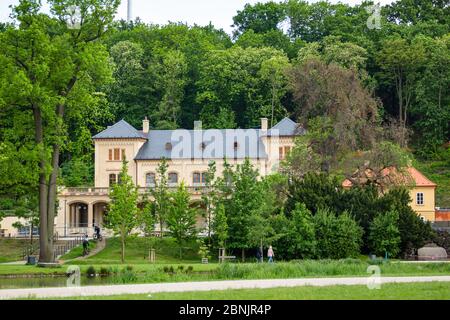 Prague, Czech Republic - May 14 2020: View of Slechtova restaurant after renovation over a park with green lawn and trees. Sunny spring day. Stock Photo