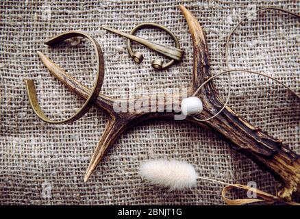 Viking era concept. Various old viking style objects on burlap textile cloth. Brooch, bracelet, glass bead on deer horn. Stock Photo
