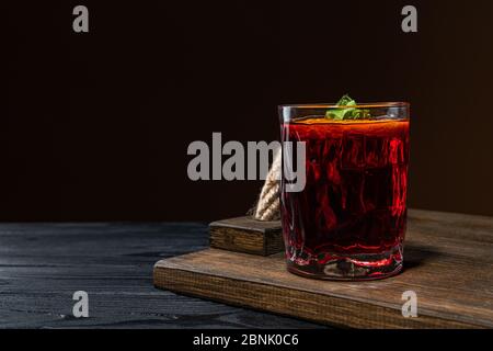 A cocktail with whiskey or cognac or Cola in a highball glass is on the counter of a dark bar Stock Photo