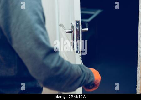 Handyman repair the door lock in the room. Man fixing lock with screwdriver, close-up of repairing door, professional locksmith installing or repairing a new deadbolt lock on a house or office. Stock Photo