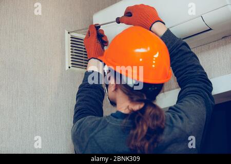 Industrial builder, handyman installing ventilation or air conditioning filter holder in wall. Technicial's occupation, repairman or engineer in protective workwear during his daily work. Stock Photo
