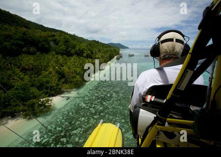 Max Ammer piloting his ultralight plane past Kri Eco Resort on Kri Island, West Papua, Indonesia. Stock Photo