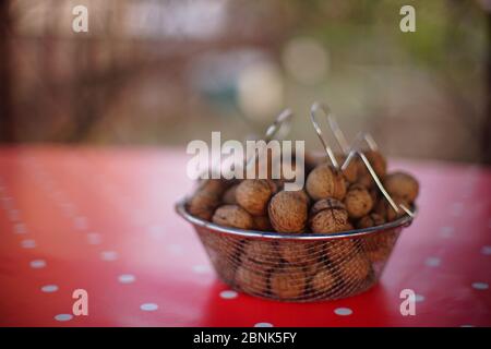 A bowl full of walnuts on a red tablecloth with white dots Stock Photo